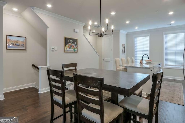 dining space featuring an inviting chandelier, sink, crown molding, and dark hardwood / wood-style floors