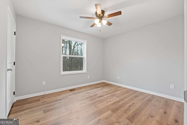 empty room with ceiling fan and light hardwood / wood-style flooring