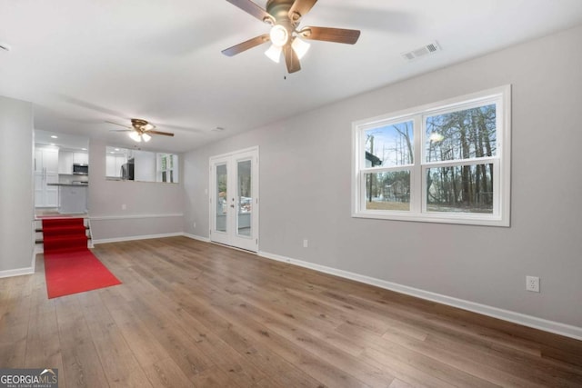 unfurnished living room featuring wood-type flooring, french doors, and ceiling fan