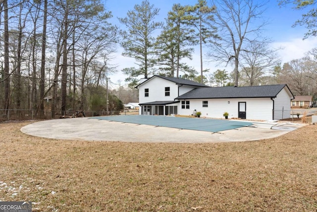 rear view of house featuring a yard, a covered pool, and a patio area