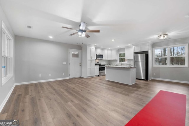 kitchen featuring white cabinetry, light hardwood / wood-style floors, stainless steel appliances, and a center island