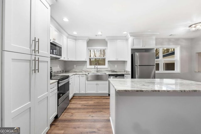 kitchen featuring dark wood-type flooring, sink, white cabinetry, light stone counters, and appliances with stainless steel finishes