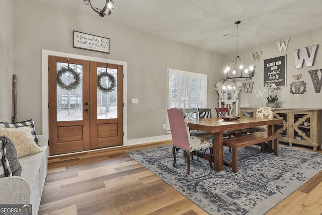 dining area featuring french doors, wood-type flooring, an inviting chandelier, and plenty of natural light