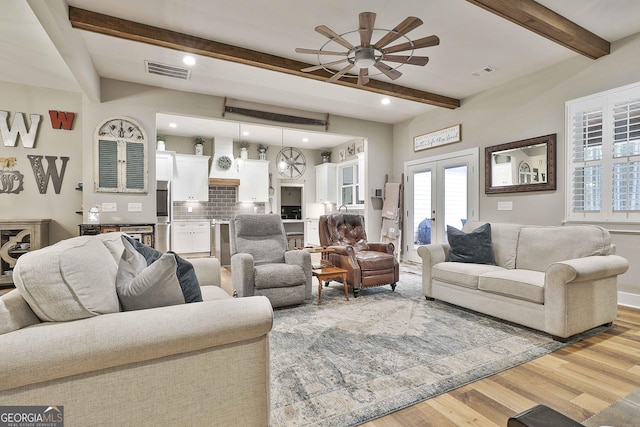 living room featuring beamed ceiling, light wood-type flooring, and french doors