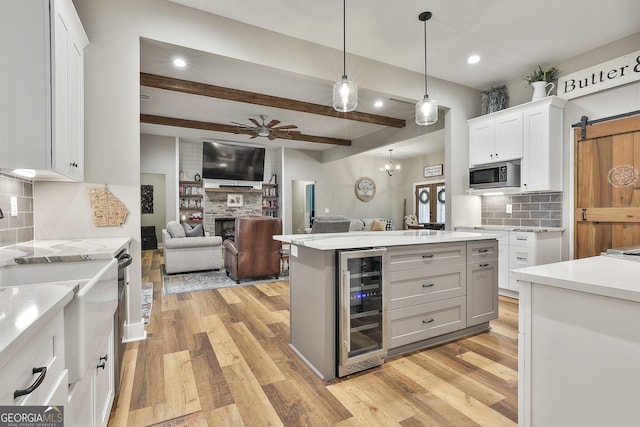 kitchen featuring pendant lighting, white cabinetry, wine cooler, light hardwood / wood-style floors, and a barn door