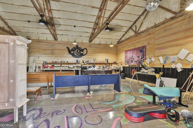 misc room featuring vaulted ceiling, wooden walls, and a workshop area