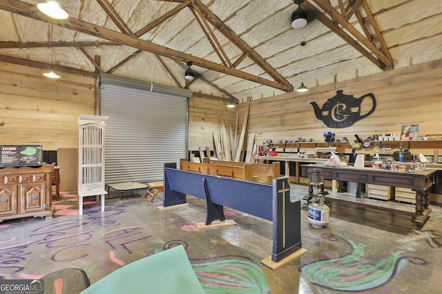 interior space with wood walls, high vaulted ceiling, concrete floors, a workshop area, and beamed ceiling