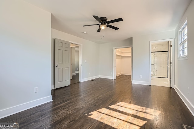 unfurnished bedroom with a closet, dark wood-type flooring, ceiling fan, and a spacious closet