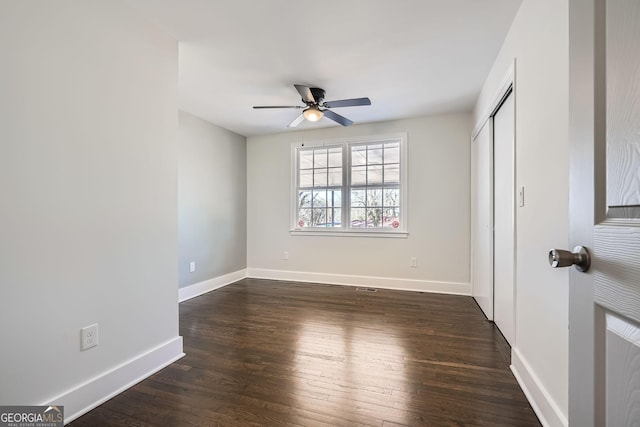 unfurnished bedroom featuring dark wood-type flooring, a closet, and ceiling fan