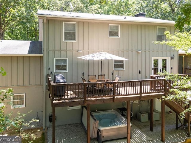 rear view of house with a wooden deck and an outdoor hot tub