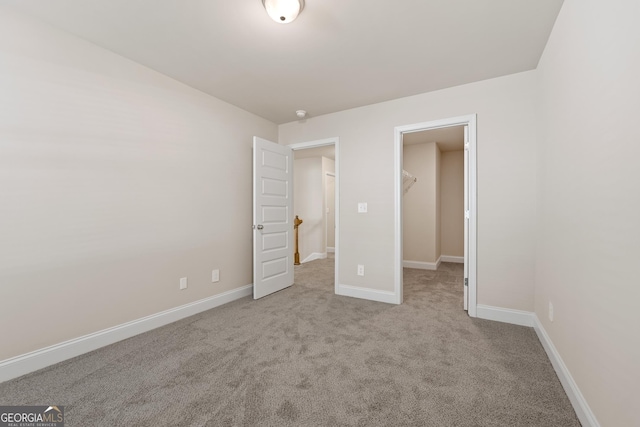 unfurnished bedroom with a spacious closet, light colored carpet, and a closet