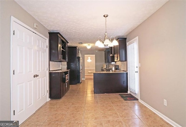 kitchen featuring hanging light fixtures, light tile patterned floors, a notable chandelier, and a textured ceiling