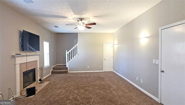 unfurnished living room with ceiling fan, a fireplace, a textured ceiling, and carpet