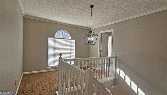 hall with crown molding, carpet flooring, a textured ceiling, and a notable chandelier