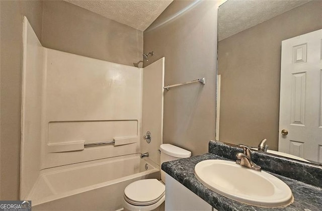 full bathroom featuring vanity, washtub / shower combination, a textured ceiling, and toilet