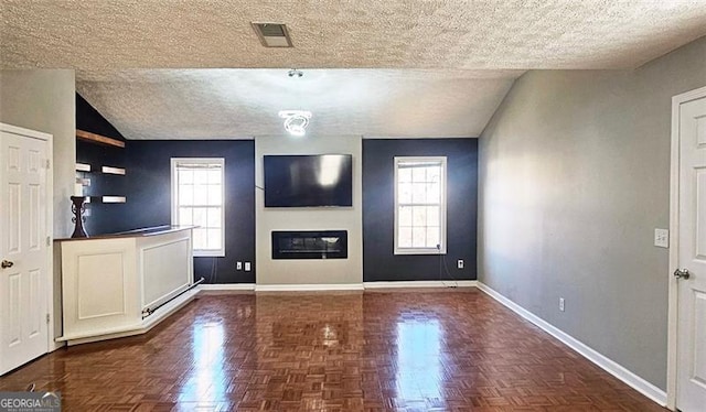 unfurnished living room with plenty of natural light, a textured ceiling, and dark parquet flooring