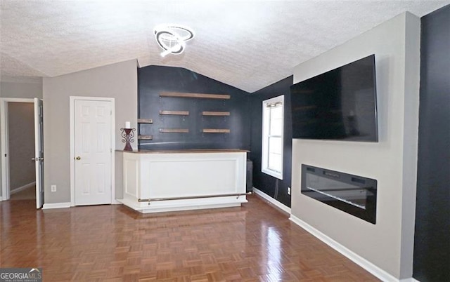 unfurnished living room with dark parquet flooring, vaulted ceiling, and a textured ceiling