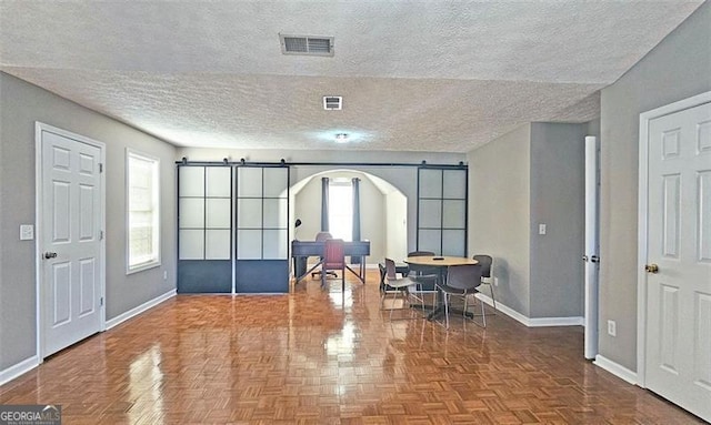 entryway featuring parquet floors, a barn door, and a textured ceiling