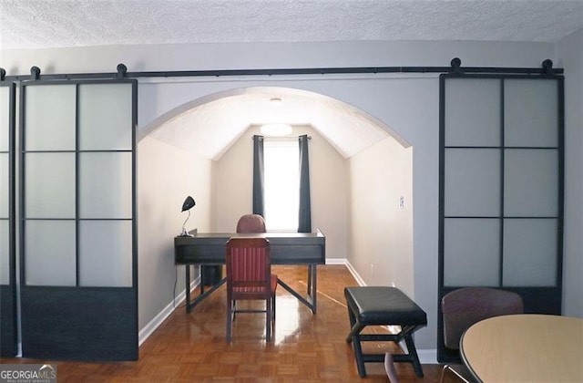 office with lofted ceiling, parquet flooring, a barn door, and a textured ceiling