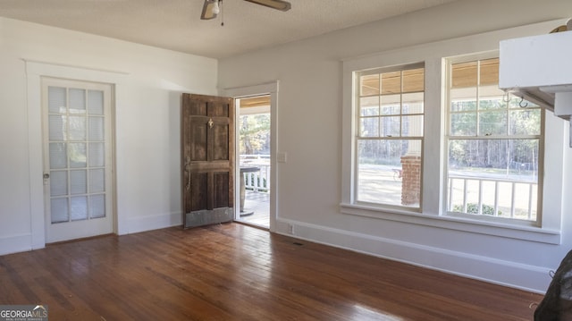 empty room featuring ceiling fan, a healthy amount of sunlight, dark hardwood / wood-style floors, and a textured ceiling