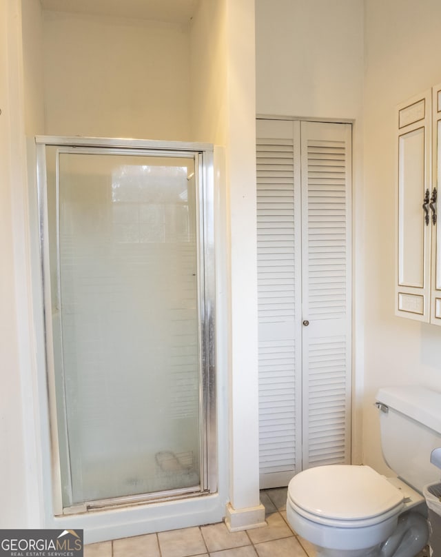 bathroom with tile patterned flooring, toilet, and walk in shower