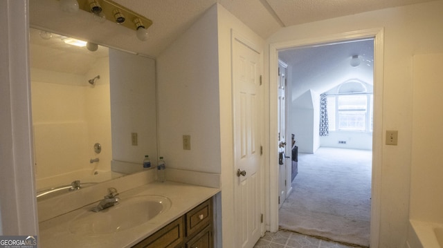 bathroom with vanity, vaulted ceiling, shower / bathing tub combination, and a textured ceiling