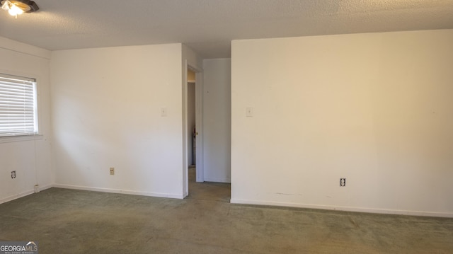 spare room with dark carpet and a textured ceiling