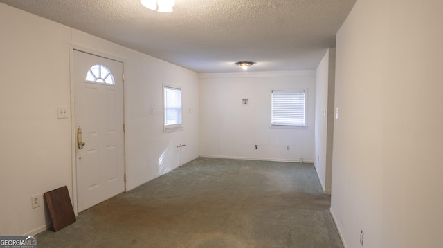 entrance foyer featuring dark colored carpet and a textured ceiling