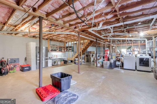 basement featuring stainless steel refrigerator, independent washer and dryer, and electric water heater