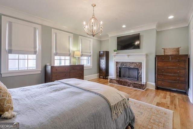 bedroom with a premium fireplace, crown molding, and light hardwood / wood-style floors