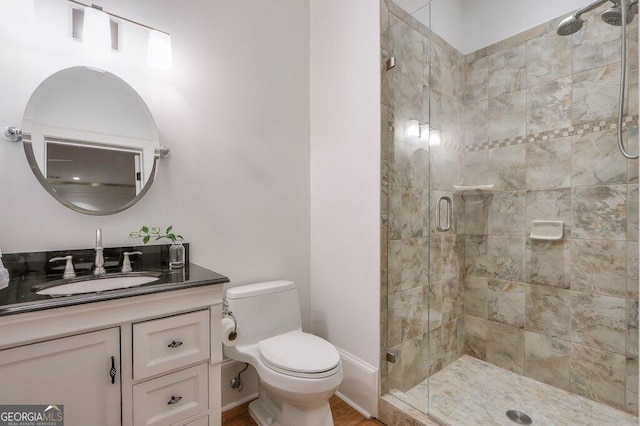 bathroom with vanity, a shower with shower door, and toilet