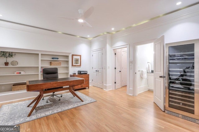 office space with crown molding, light hardwood / wood-style floors, and beverage cooler