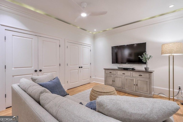 living room with crown molding, ceiling fan, and light wood-type flooring