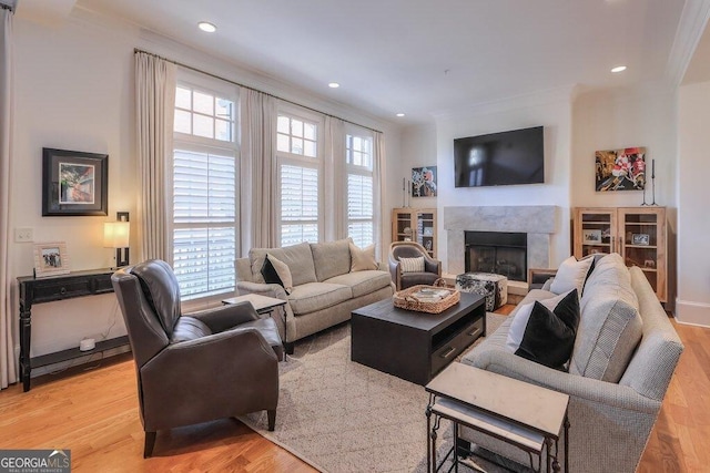 living room featuring a premium fireplace, crown molding, and light wood-type flooring