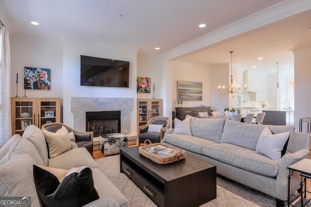 living room with an inviting chandelier, a premium fireplace, and crown molding