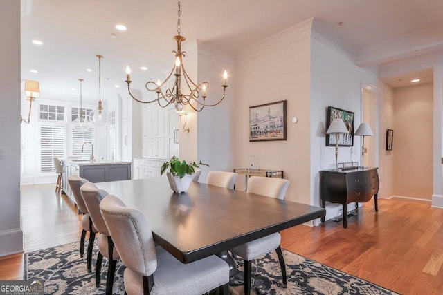 dining space with crown molding, sink, and light wood-type flooring