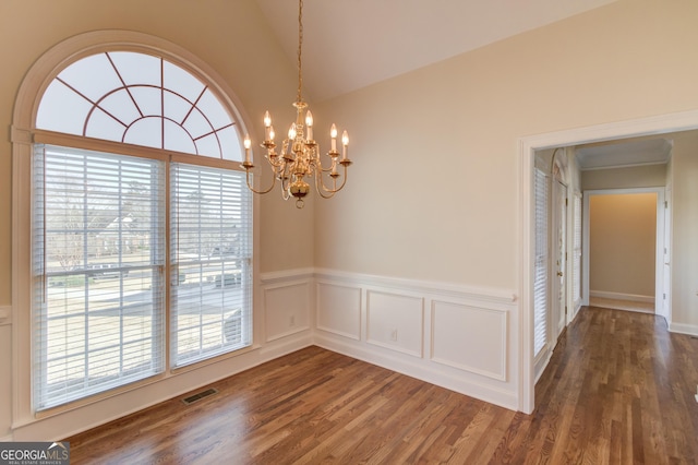 unfurnished dining area featuring dark hardwood / wood-style flooring, a notable chandelier, and vaulted ceiling