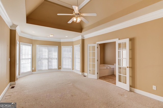 spare room with crown molding, ceiling fan, a raised ceiling, light carpet, and french doors