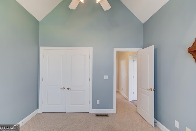 unfurnished bedroom with ceiling fan, light carpet, high vaulted ceiling, and a closet