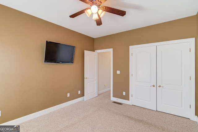 unfurnished bedroom with light colored carpet, a closet, and ceiling fan