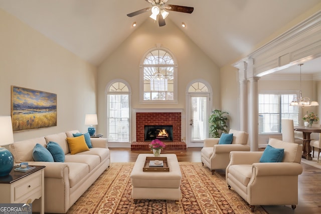 living room with a brick fireplace, ceiling fan with notable chandelier, high vaulted ceiling, and light hardwood / wood-style floors