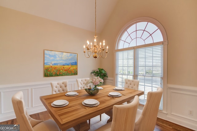 dining room with dark wood-type flooring, lofted ceiling, and a notable chandelier