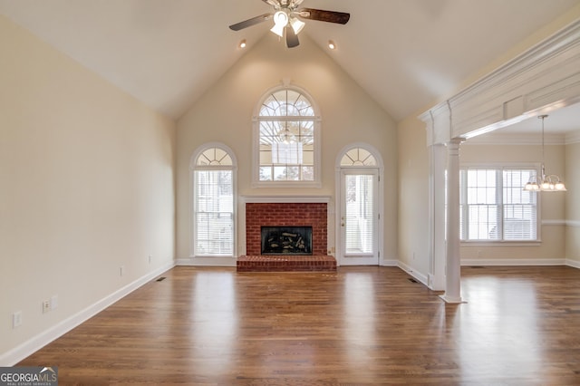 unfurnished living room featuring dark hardwood / wood-style flooring, a fireplace, high vaulted ceiling, and ornate columns