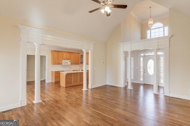 unfurnished living room with ornate columns, hardwood / wood-style flooring, a healthy amount of sunlight, and ceiling fan