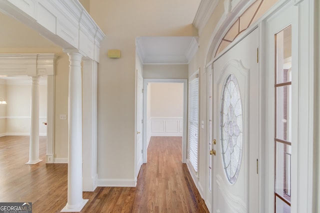 foyer entrance with dark hardwood / wood-style flooring, crown molding, and ornate columns