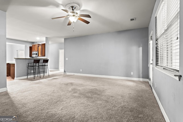 unfurnished living room featuring light carpet and ceiling fan