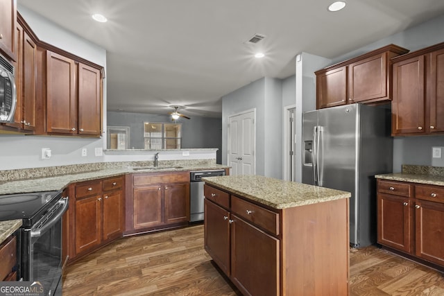 kitchen featuring sink, stainless steel appliances, light stone counters, a kitchen island, and dark hardwood / wood-style flooring