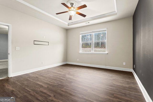 unfurnished room featuring a tray ceiling, dark wood-type flooring, and ceiling fan