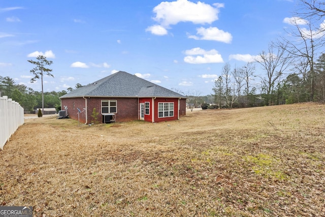 rear view of property featuring cooling unit and a lawn