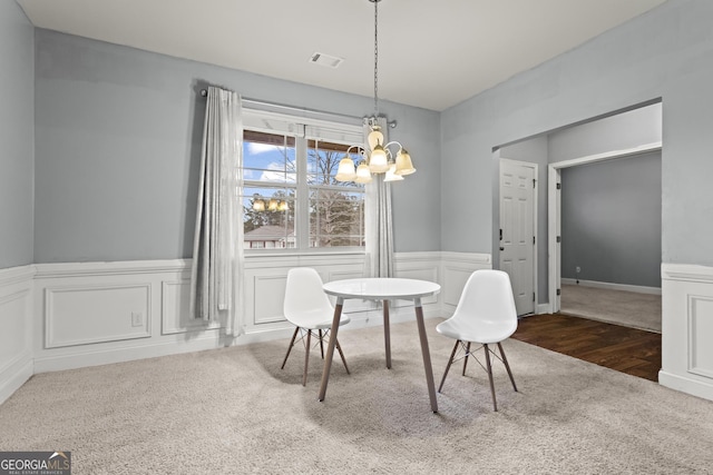 carpeted dining room with a chandelier